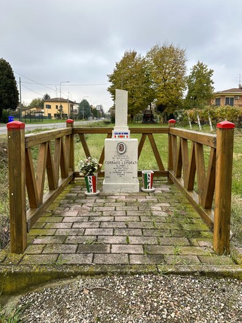Cippo commemorativo a Leporati, dedicato a Corrado Leporati, circondato da un giardino curato.