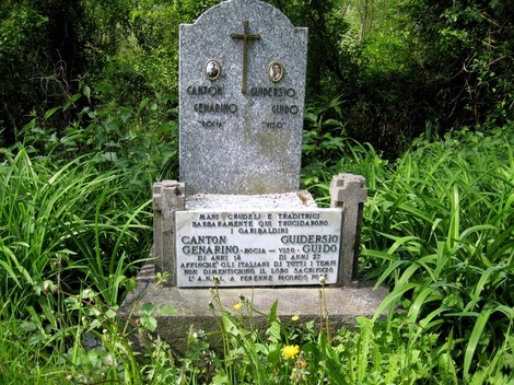 Cippo commemorativo dedicato a Canton e Guiderso, immerso nella vegetazione.