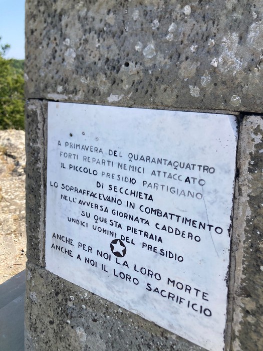 Monumento in Secchieta con iscrizione commemorativa che ricorda la resistenza e il sacrificio dei partigiani.