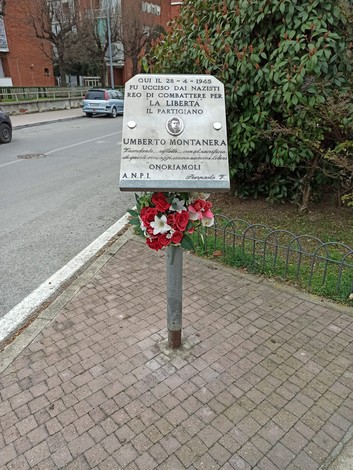 Lapide dedicata a Umberto Montanera, partigiano ucciso dai nazisti, con fiori di commemorazione.