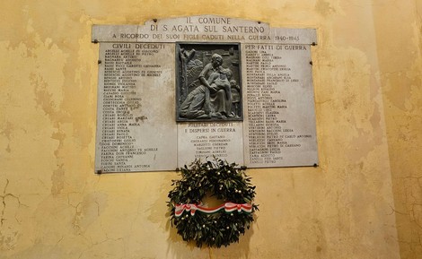 Lapide commemorativa ai caduti di Sant'Agata, con nomi di soldati e un omaggio floreale.