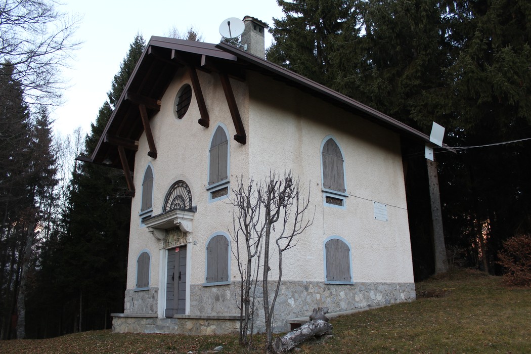 Edificio storico con facciata chiara, finestre con persiane, immerso nella natura circostante.