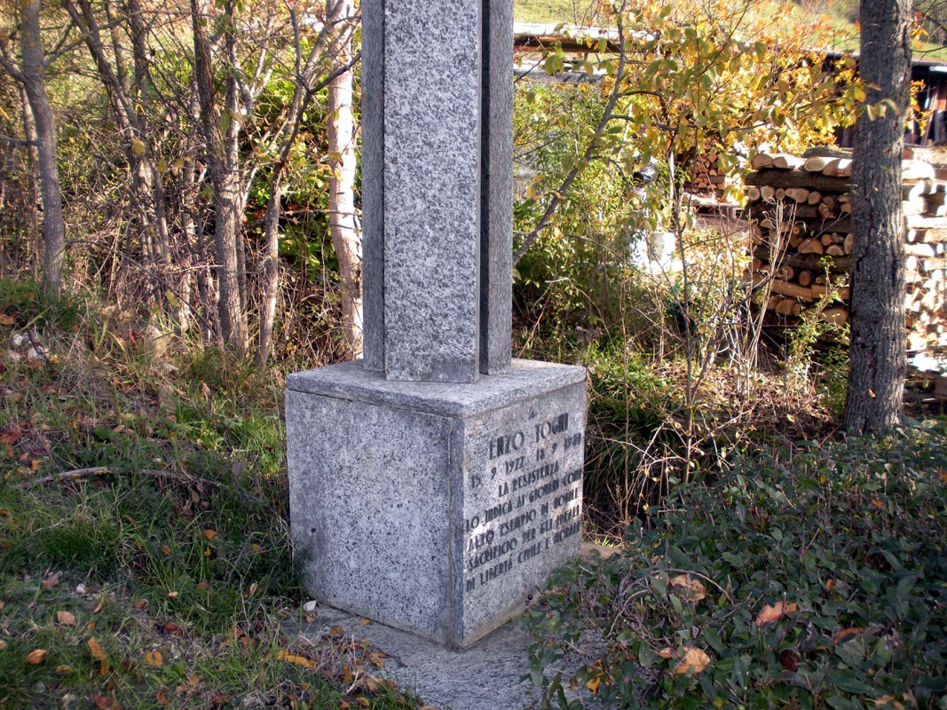 Cippo commemorativo in granito, immerso nella natura, testimonia la memoria storica della zona.