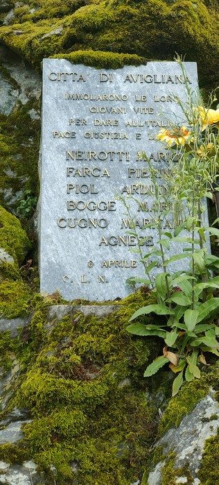 Lapide commemorativa dedicata a Neirotti e altri, immersa nella natura, in memoria di coloro che hanno dato la vita.