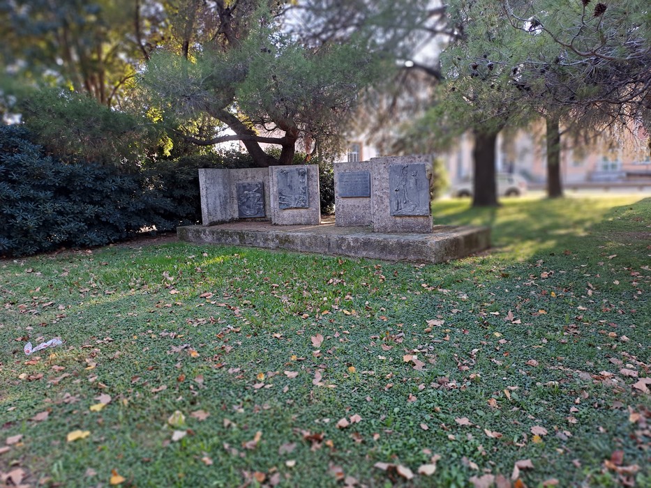 Monumento ai Caduti immerso nel verde, composto da lastre in pietra dedicate ai caduti della guerra.