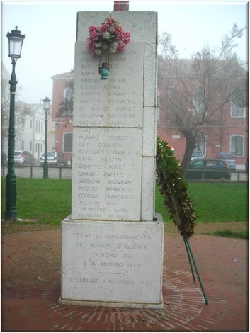 Monumento commemorativo con nomi di vittime del bombardamento, immerso in un'atmosfera nebbiosa.