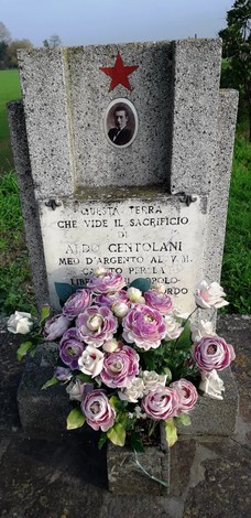 Monumento a Centolani, commemorazione con fiori e foto, simbolo di memoria e sacrificio.