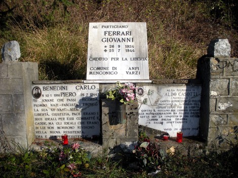 Monumento commemorativo dedicato ai partigiani Ferrari, Benedini e Casotti, con lapidi e fiori.