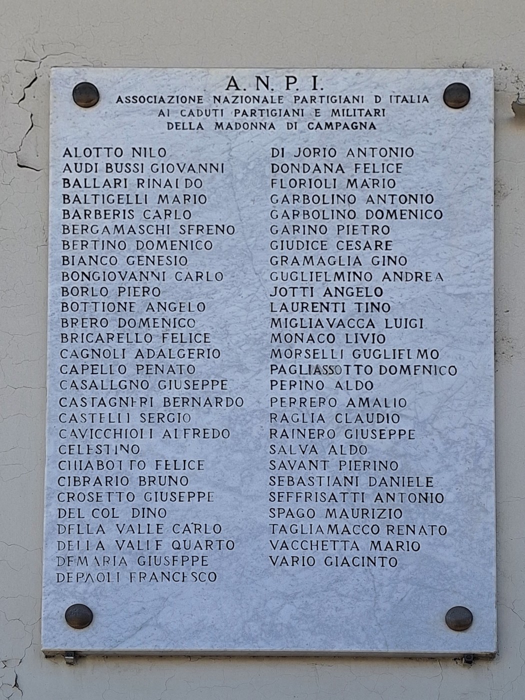 Lapide commemorativa dedicata ai caduti e partigiani della Madonna di Campagna, con elenco di nomi.