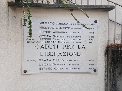 Lapide commemorativa in onore dei caduti per la liberazione, con nomi e date incisi su una placca.