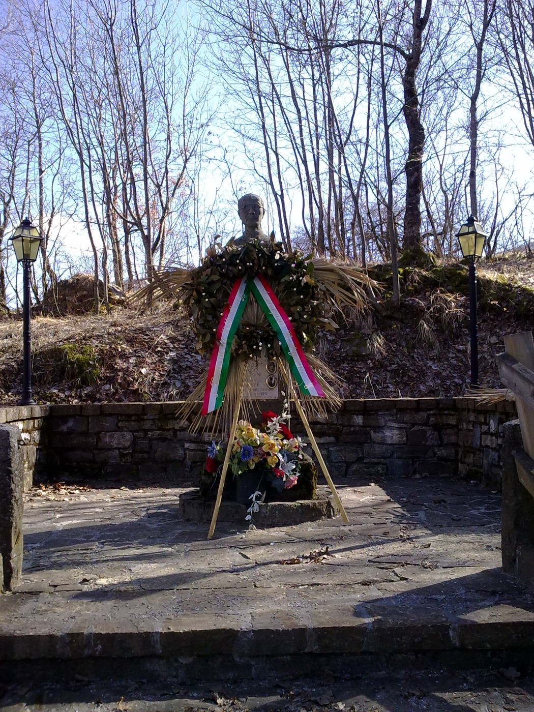 Monumento dedicato a Borghi e ai caduti in guerra, adornato con fiori e ghirlande, immerso nel verde.