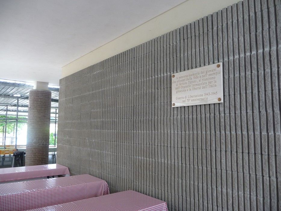 Lapide commemorativa alla Banda Turani in un contesto architettonico semplice e moderno.