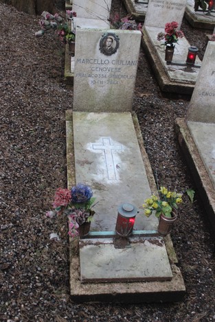 Tombe nel cimitero dedicate ai caduti per la Libertà, con fiori e lumini accesi in ricordo.