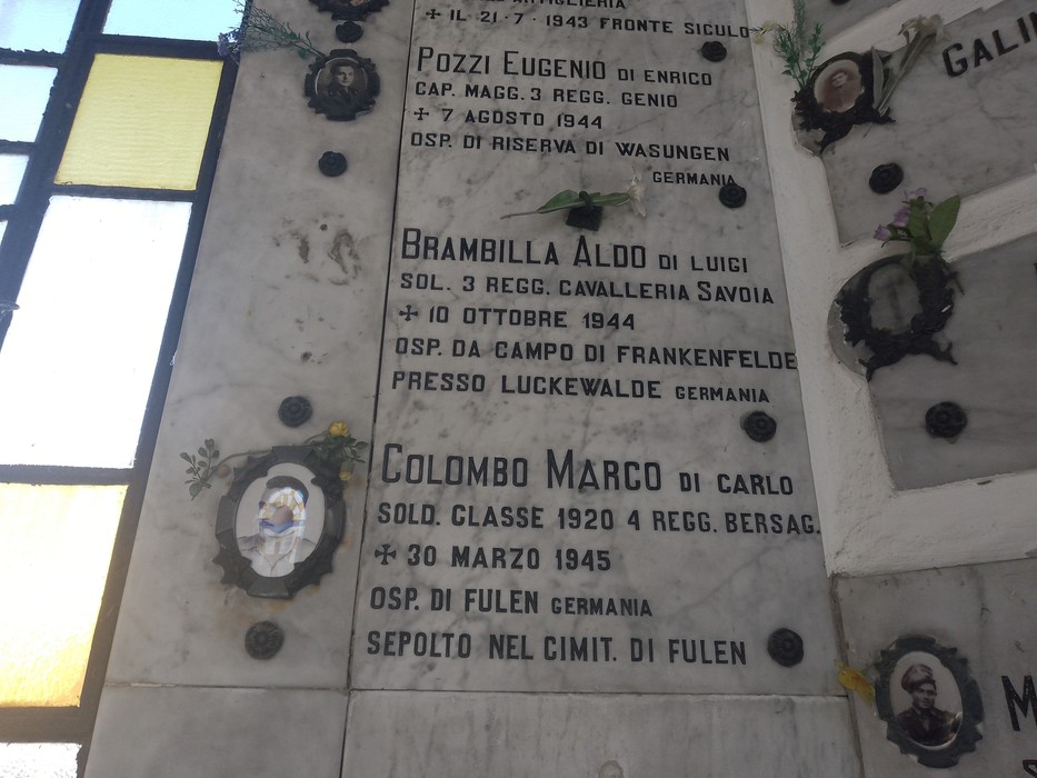 Lapidi commemorative di soldati caduti per la libertà, adornate con fiori e immagini.