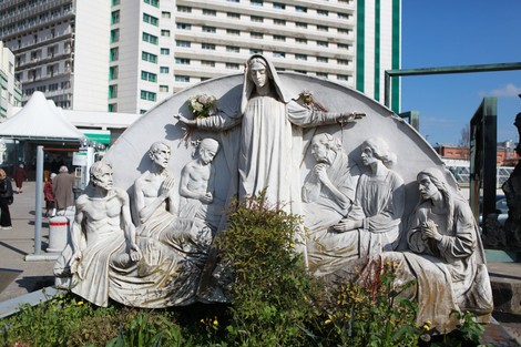 Monumento al bombardamento dell'Ospedale Maggiore, con sculture che rappresentano figure umane in celebrazione e commemorazione.