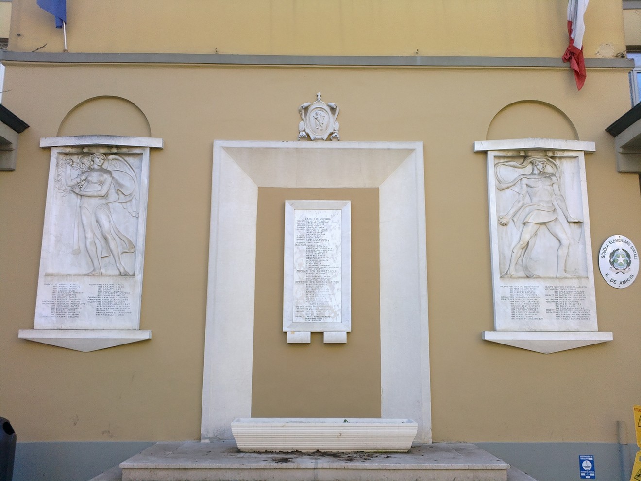 Lapide commemorativa ai caduti di Cavriago, con rilievi e iscrizioni in memoria dei combattenti.