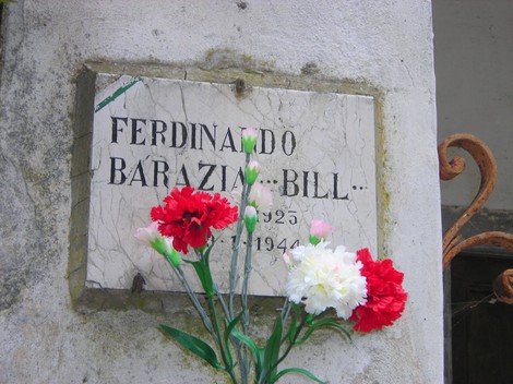 Lapide commemorativa di Ferdinando Barazia, decorata con fiori colorati, a ricordo di una figura storica.