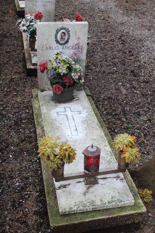 Tombe perpetue decorate con fiori e candele, dedicate ai caduti per la Libertà. Atmosfera di rispetto e memoria.