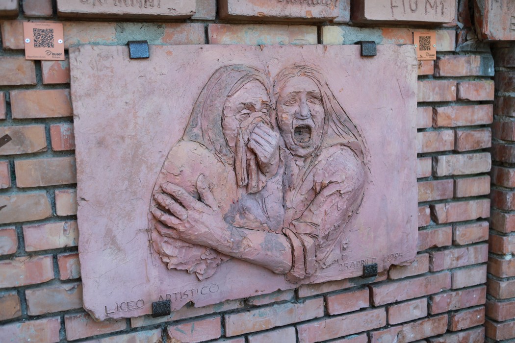 Rilievo commemorativo che rappresenta due donne in abbraccio, simbolo di resistenza e lotta per la libertà.