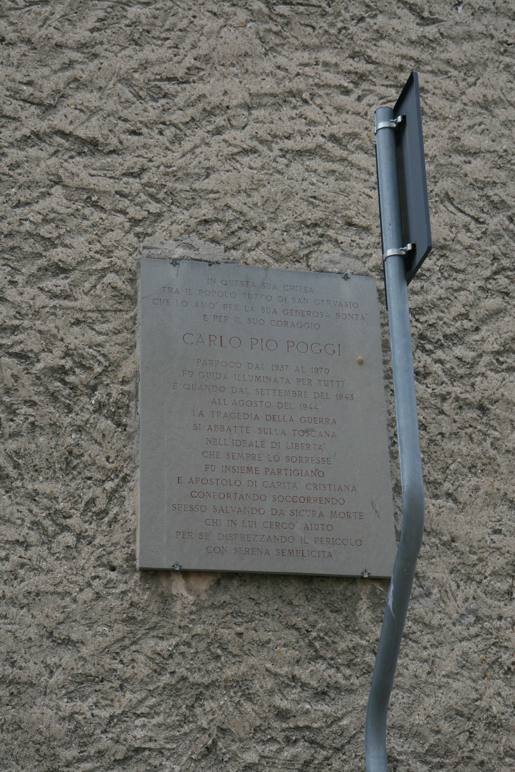 Lapide commemorativa dedicata a Don Poggi, con iscrizioni in memoria della sua vita e opere.