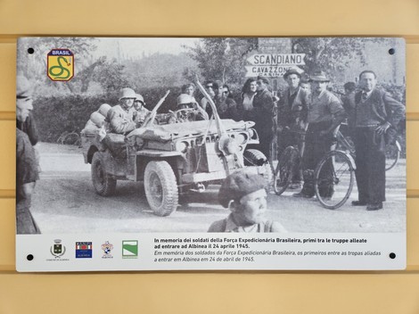 Targa commemorativa dedicata alla FEB, con un'immagine storica di soldati e un veicolo militare.