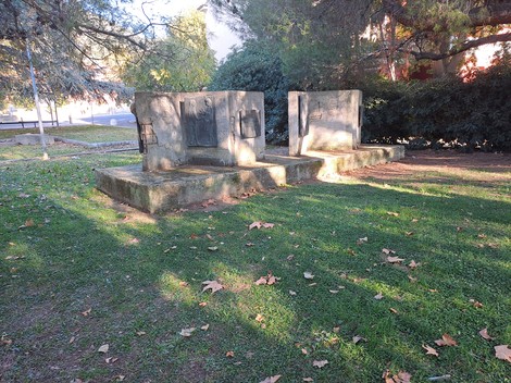 Monumento ai Caduti immerso in un verdeggiante giardino, con lastre commemorative su basi in pietra.