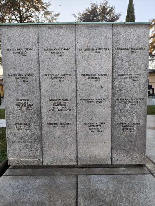 Monumento commemorativo con nomi di caduti, situato nel "Campo della Gloria", in un ambiente sereno e curato.