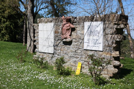 Monumento in pietra dedicato alla battaglia di Ca' di Malanca, circondato da verde e fiori.