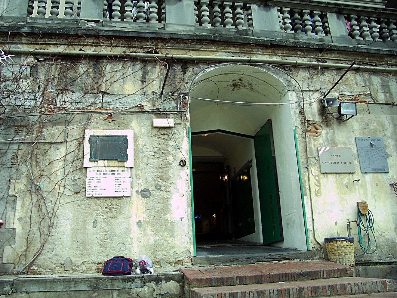 Lapide della Società Canottieri all'ingresso di un edificio storico, con pareti affrescate e dettagli architettonici.