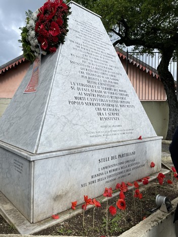Monumento dedicato ai partigiani con decorazioni floreali, situato in un'area commemorativa.