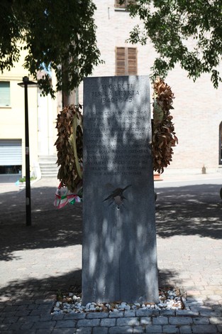 Monumento ai Caduti per la libertà, con decorazioni floreali e un'ambientazione urbana tranquilla.