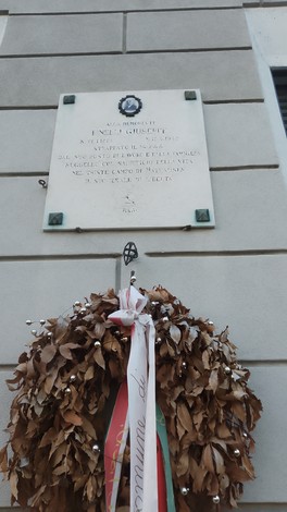 Lapide commemorativa a Rinelli, con una corona di foglie e nastro tricolore in memoria di eventi storici.