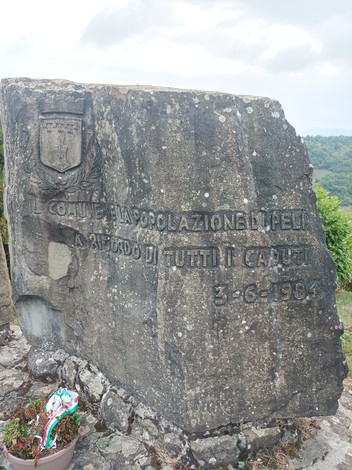 Monumento ai caduti, realizzato in pietra, con iscrizioni commemorative e vista panoramica sul paesaggio circostante.