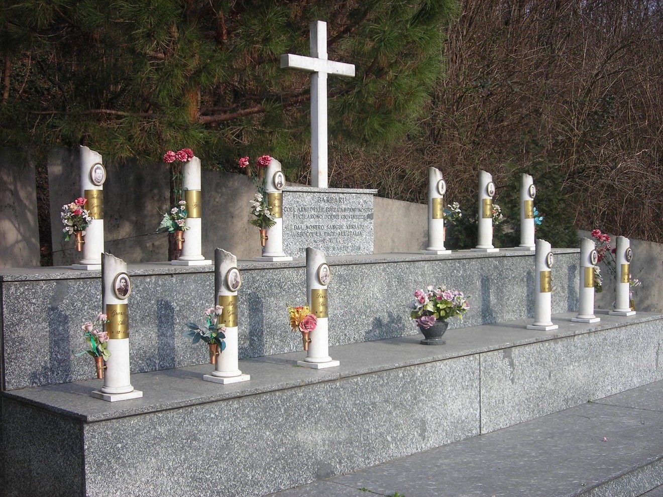 Monumento commemorativo ai martiri della Garella con colonne, fiori e una croce.