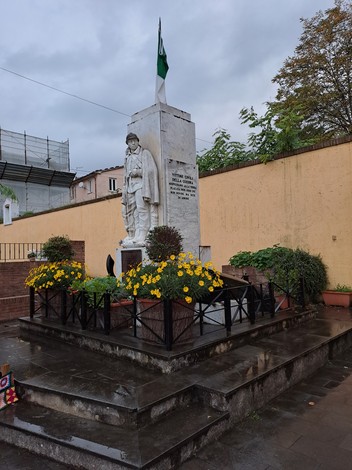 Monumento ai caduti di Strettoia, con statue e fiori, in memoria dei soldati locali.