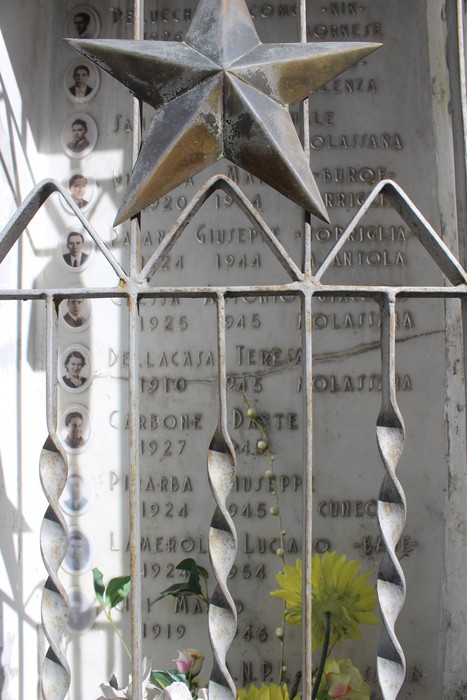 Cappella ai caduti di Molassana con decorazioni metalliche e iscrizioni commemorative. Fiori adornano l'area.