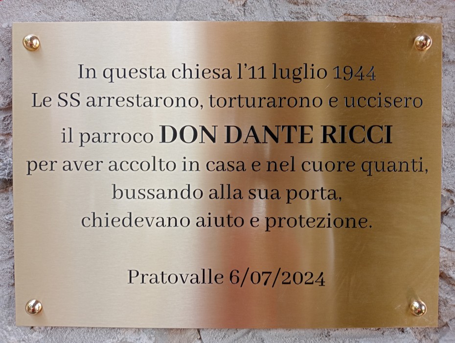 Targa commemorativa in memoria di Don Dante Ricci, martire della Seconda Guerra Mondiale, affissa in una chiesa.