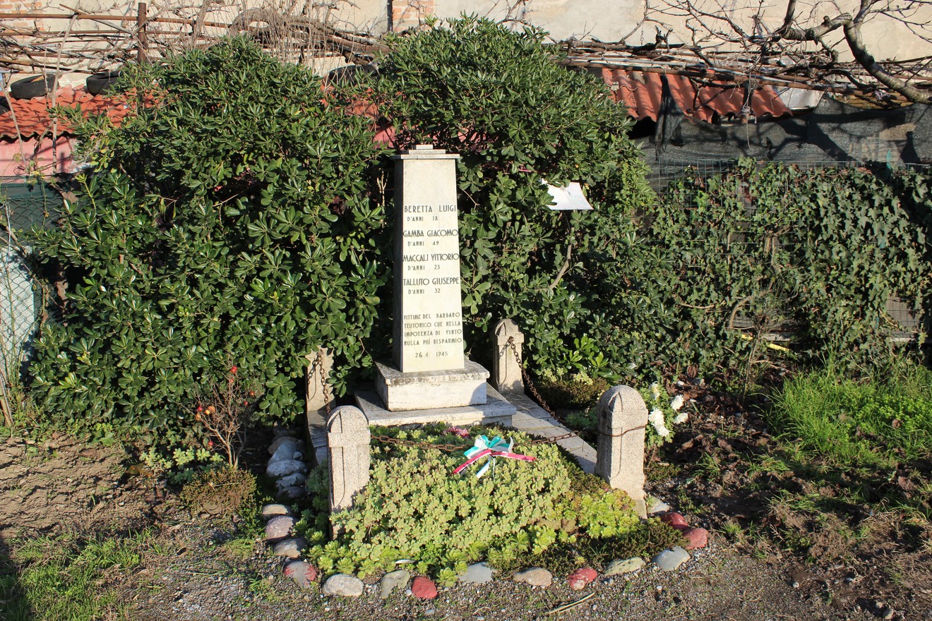 Monumento ai caduti dell'Insurrezione, circondato da vegetazione e adornato con fiori e decorazioni.