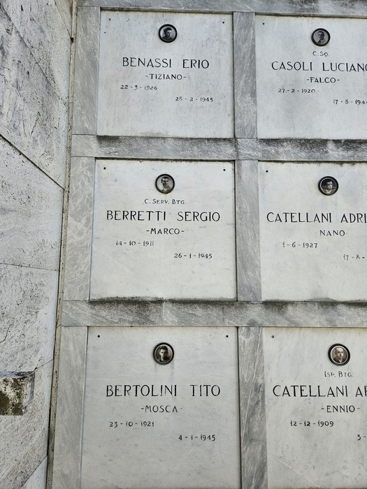 Monumento ai Caduti Partigiani con targhe commemorative di diversi combattenti e date significative.
