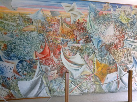 Murale colorato che celebra la pace, con manifestanti, bandiere e simboli di unità e speranza.
