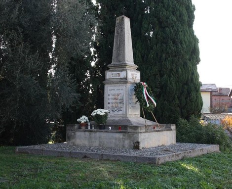 Monumento ai caduti di Santa Maria, con cippo e decorazioni floreali, immerso in un contesto verde.