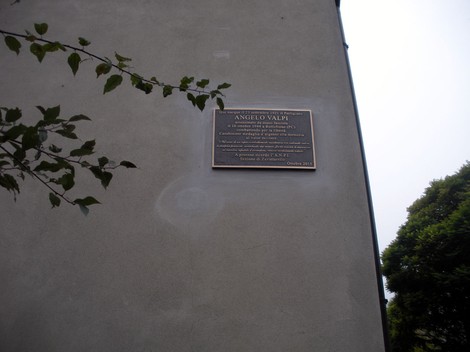 Targa commemorativa dedicata ad Angelo Valpi su un muro, in un contesto urbano.