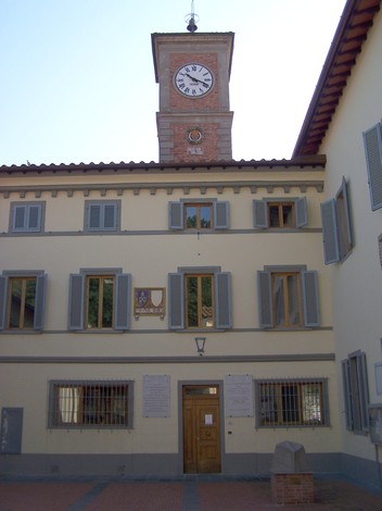 Lapide commemorativa affissa su un edificio storico con orologio, che celebra un'importante ricorrenza.