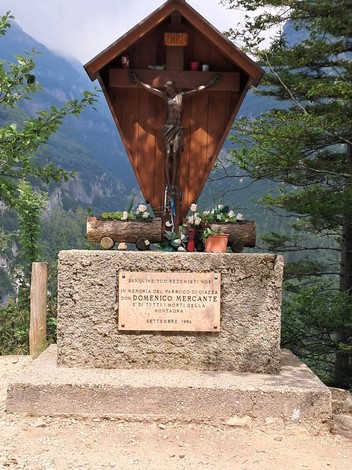 Monumento commemorativo dedicato a Don Domenico Mercante, situato in un suggestivo paesaggio montano.