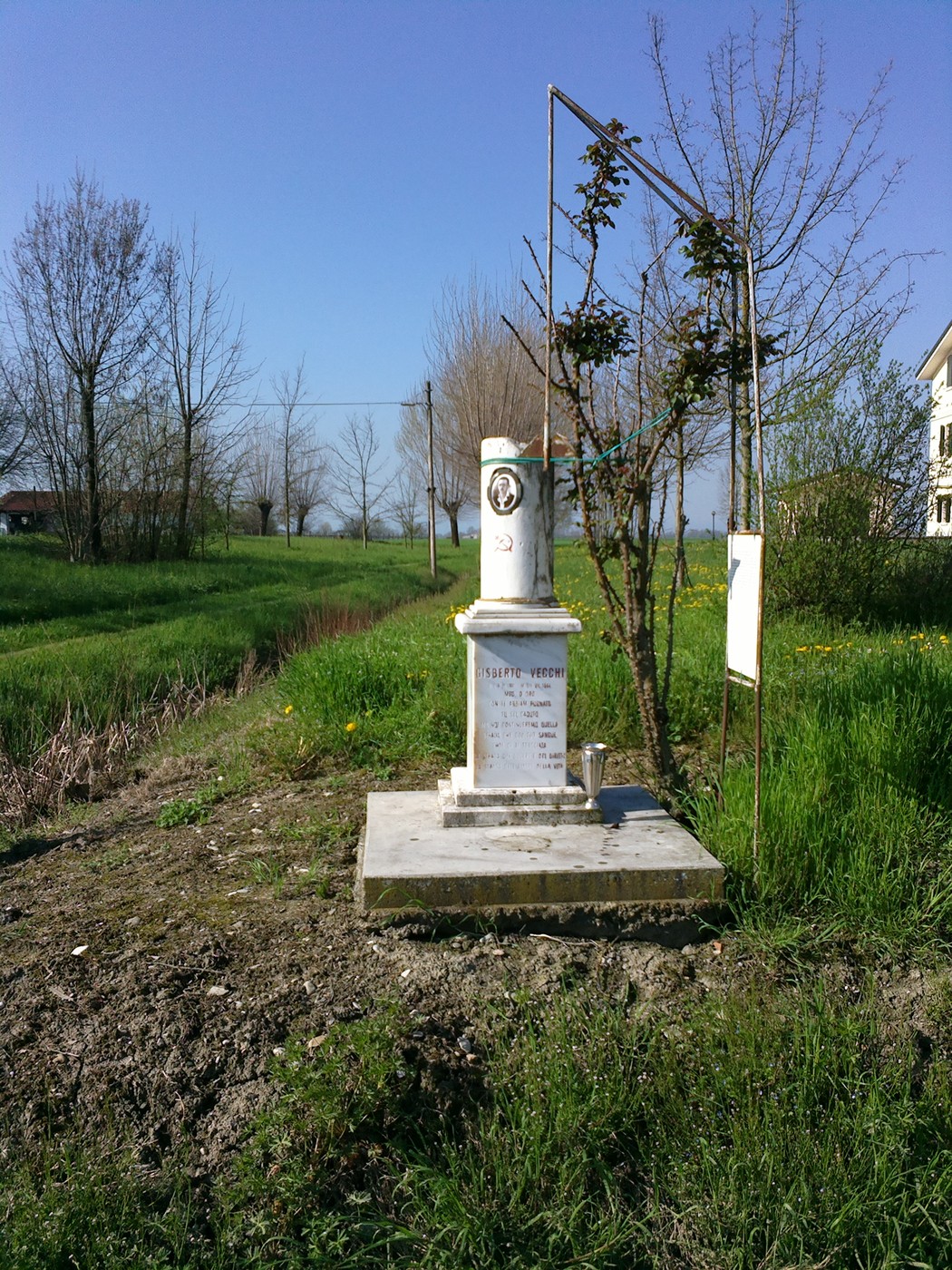 Cippo a Vecchi: monumento bianco immerso nel verde, circondato da alberi e natura.