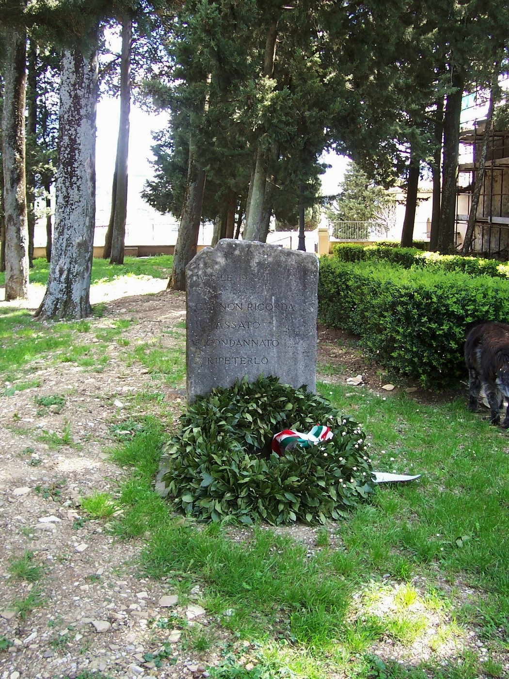 Cippo commemorativo dedicato ai rastrellamenti d'aprile, circondato da alberi e vegetazione.
