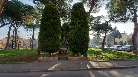 Monumento commemorativo alle vittime del primo bombardamento su Imola, circondato da alberi e verde.