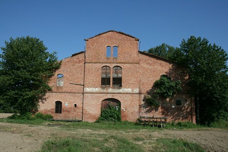 Lapide della Tabaccaia di Prato Grande, edificio storico in mattoni circondato da verde.