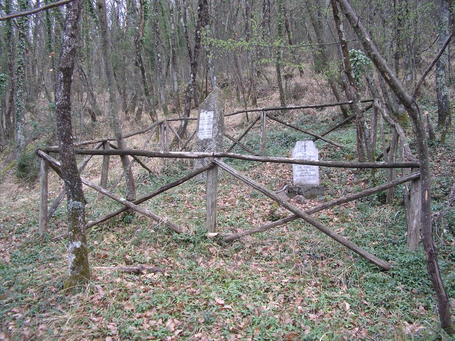 Cippo commemorativo dedicato a Ferruzzi e Calvelli, immerso nella natura tra alberi e vegetazione.