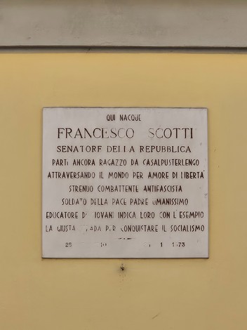 Lapide commemorativa dedicata a Francesco Scotti, senatore della Repubblica, situata su una parete.